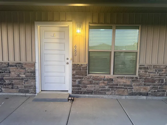 Entrance to property featuring stone siding, a porch, and board and batten siding