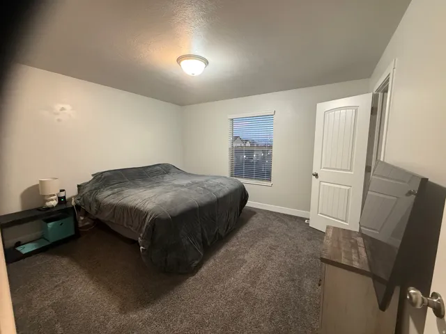 Bedroom featuring dark carpet and a textured ceiling