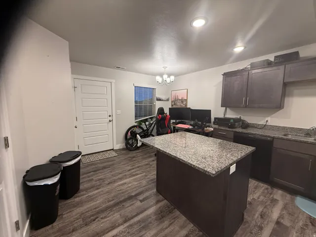 Kitchen featuring dark wood finish cabinets, a center island, hanging lights, dishwasher, and dark wood-type flooring