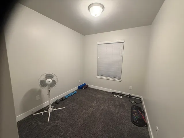 Unfurnished room featuring baseboards and dark carpet
