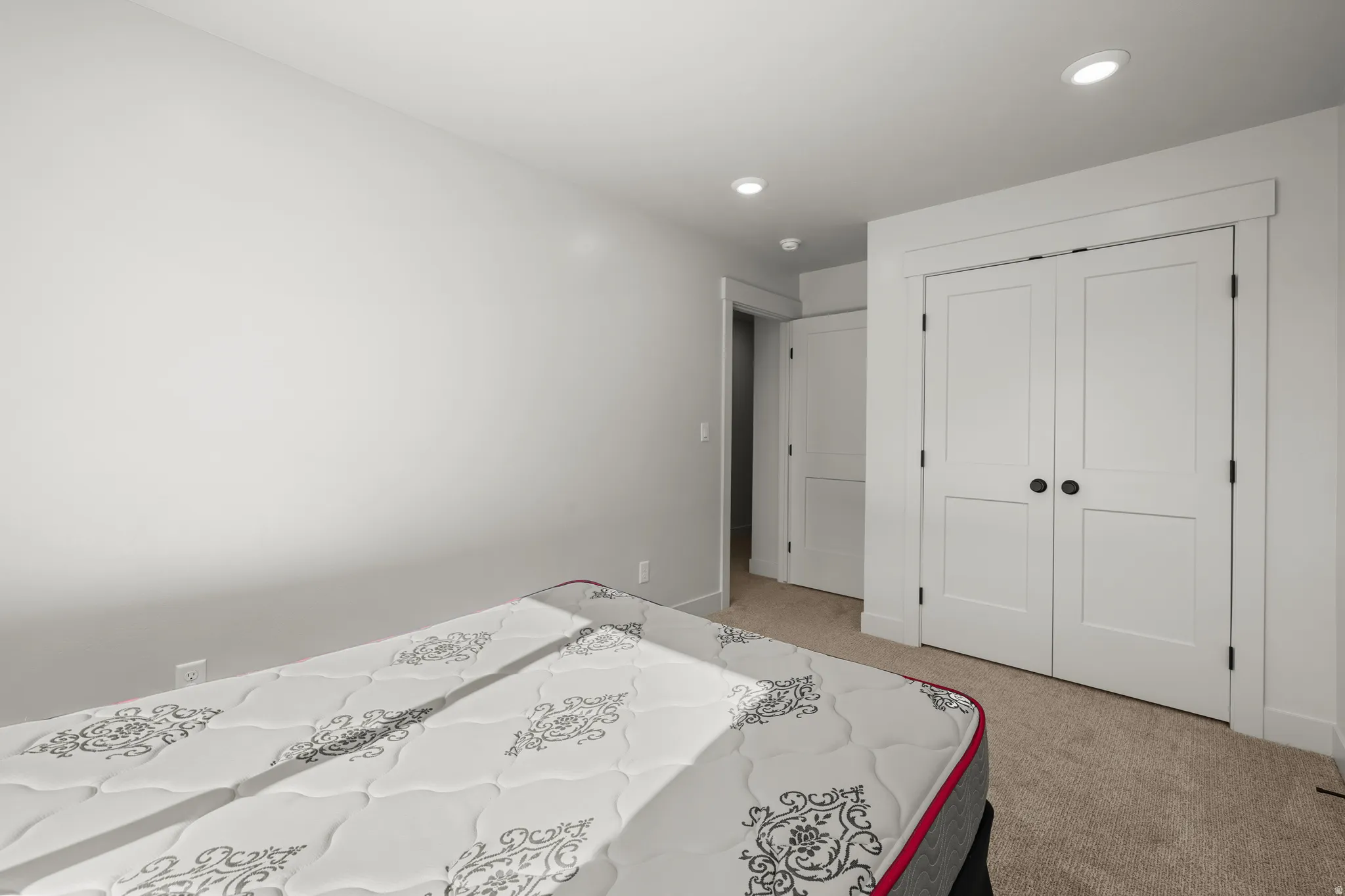 Bedroom 1 with light carpet, a closet, and recessed lighting