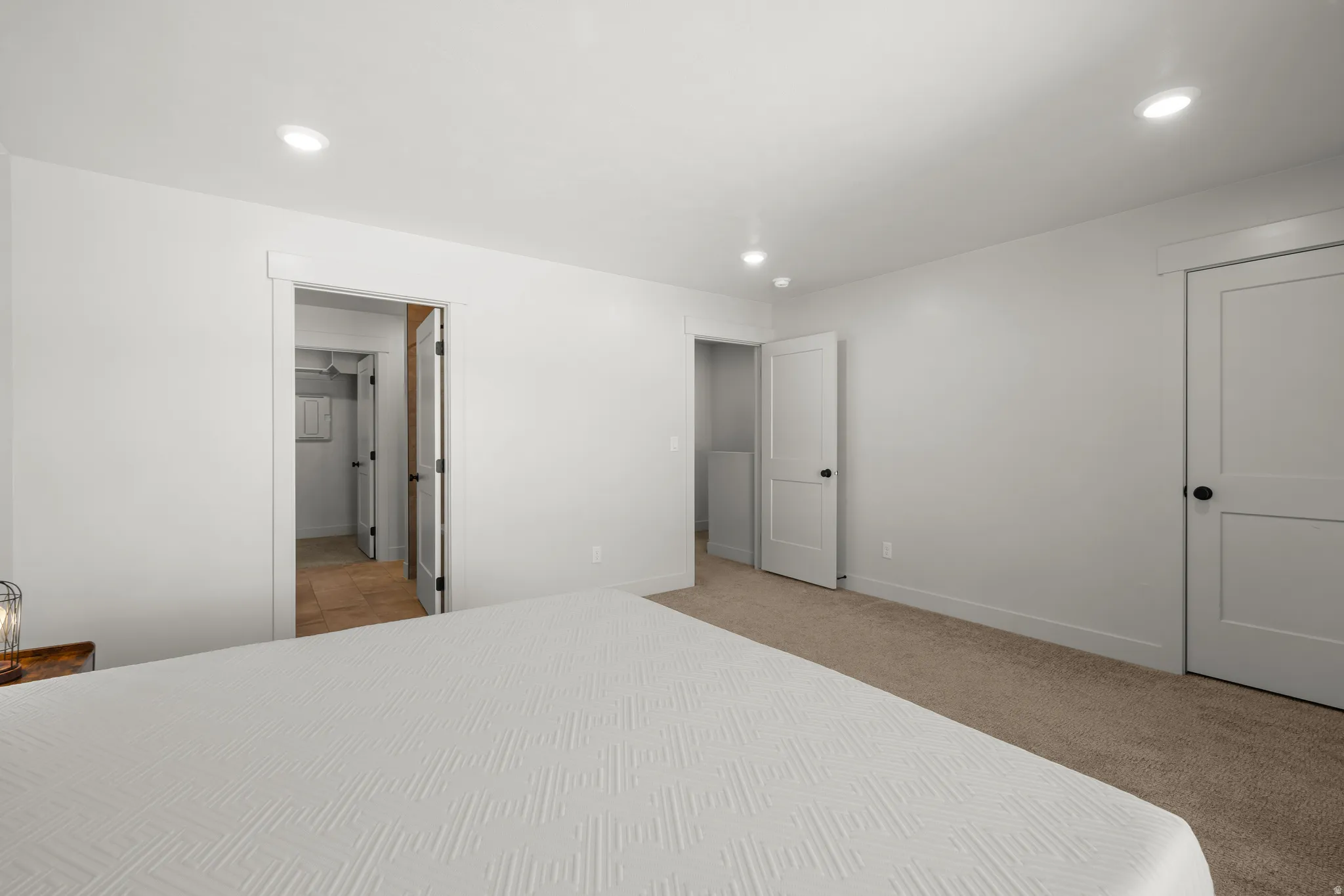 Primary bedroom with light colored carpet, recessed lighting and ensuite bathroom