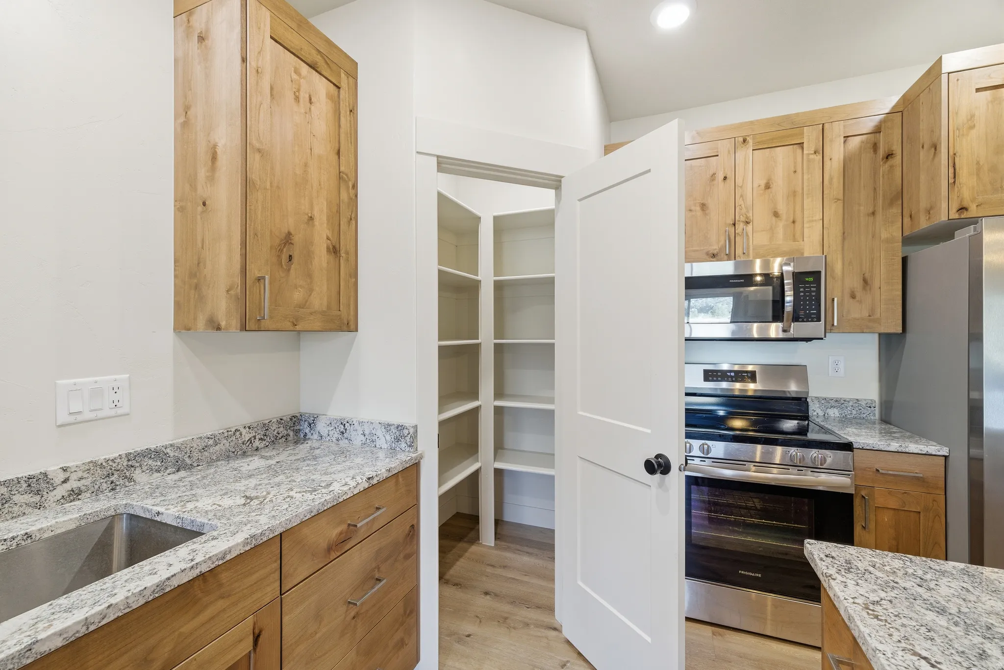 Kitchen featuring stainless steel appliances, light stone countertops, light wood-style floors, and recessed lighting