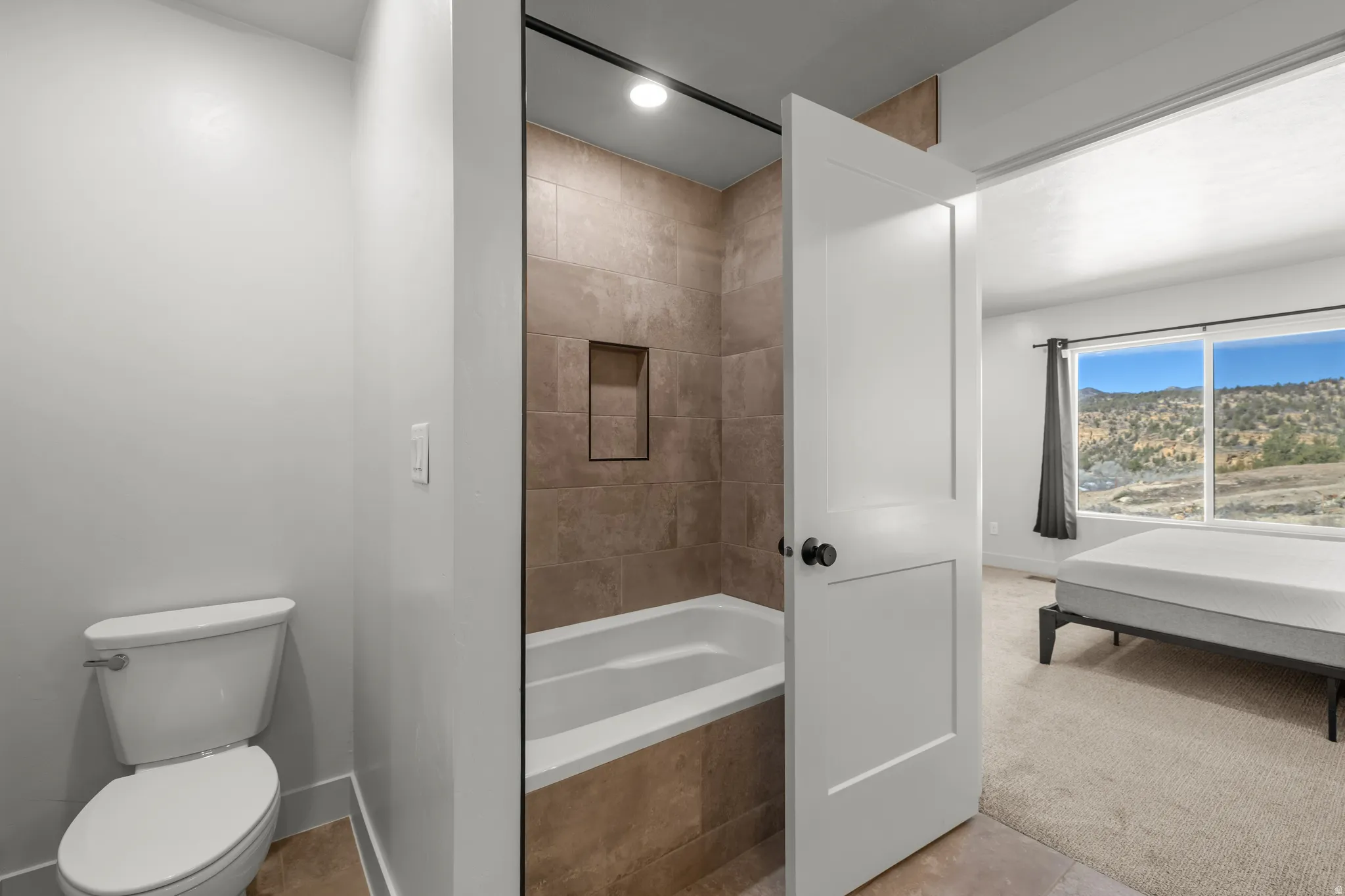 Ensuite bathroom with tiled shower / bath combo and recessed lighting
