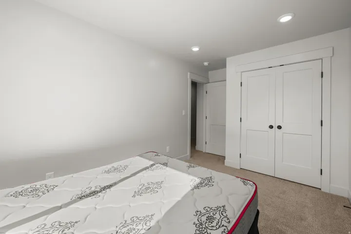 Bedroom 1 with light carpet, a closet, and recessed lighting