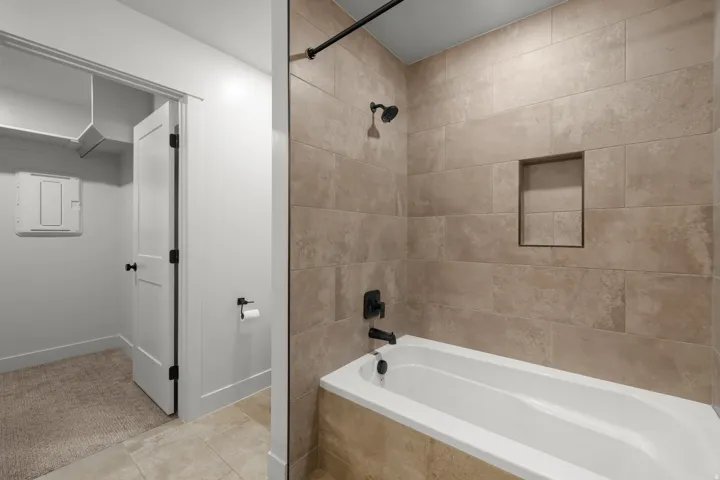 Ensuite bathroom featuring tiled shower / bath combo and light tile patterned floors