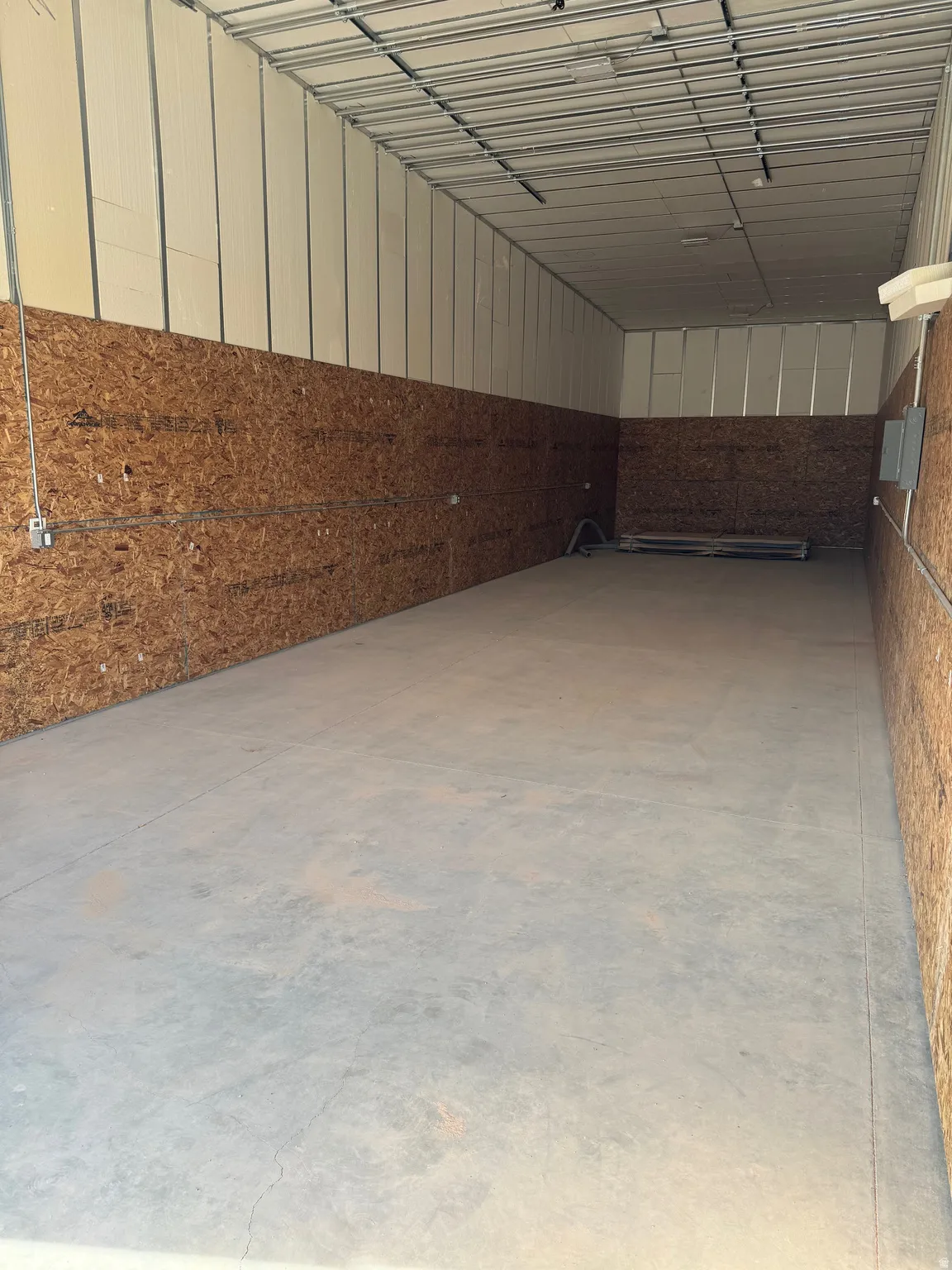Miscellaneous room featuring unfinished concrete flooring and a garage
