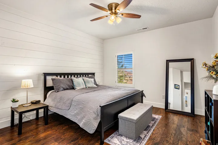 Bedroom featuring dark wood-type flooring, a ceiling fan, wood walls, and a textured ceiling