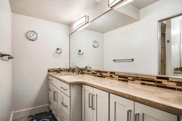 Full bath featuring vanity, tasteful backsplash, and a shower