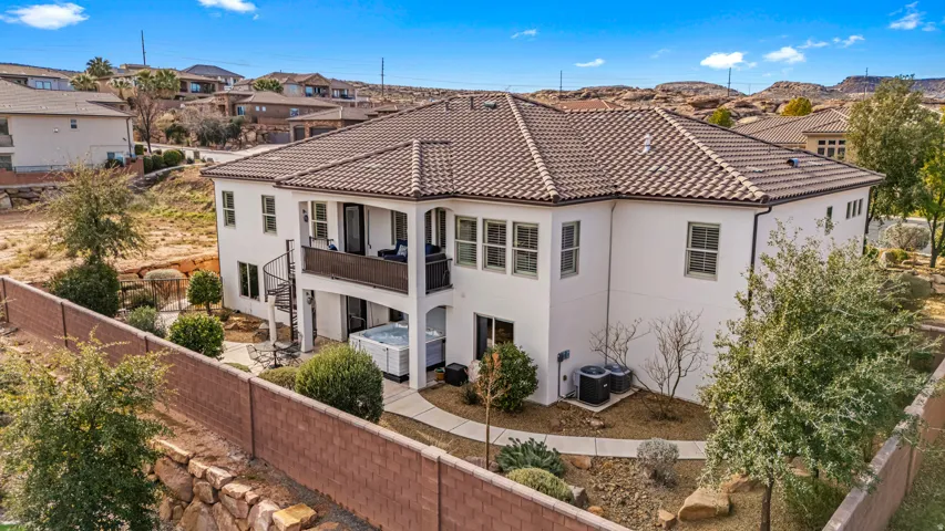 Back of property with a fenced backyard, stucco siding, a balcony, a tile roof, and a residential view