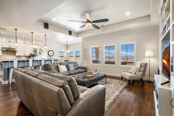 Living area featuring a tray ceiling, recessed lighting, a ceiling fan, dark wood-type flooring, and a textured ceiling
