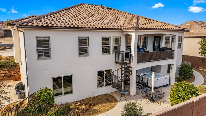 Back of property with a tile roof, a fenced backyard, stucco siding, a hot tub, and a patio area