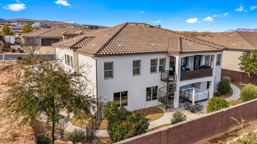Back of property featuring a fenced backyard, a balcony, stucco siding, a tiled roof, and a patio