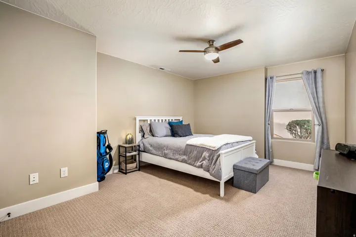 Bedroom featuring light carpet, ceiling fan, and a textured ceiling