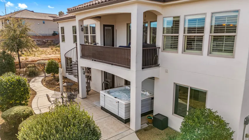 Back of house featuring a hot tub, a patio area, stucco siding, a balcony, and a tile roof