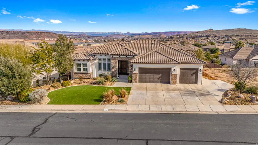 Mediterranean / spanish-style house with a garage, a front lawn, a mountain view, driveway, and stone siding