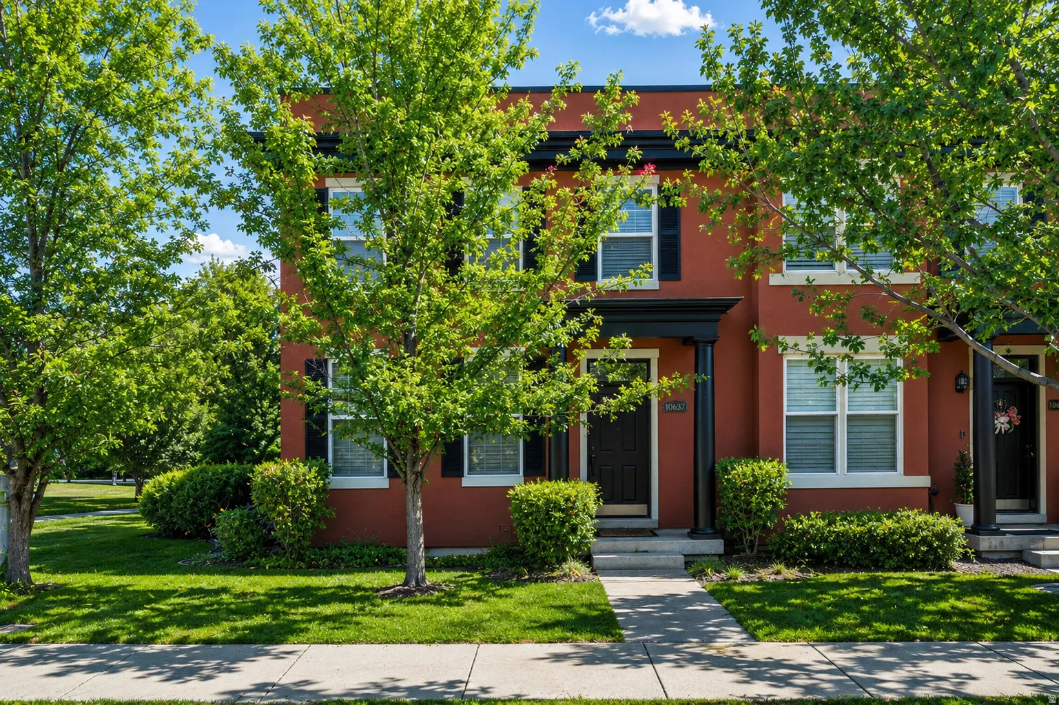 Red stucco exterior featuring white window trim and black decorative shutters