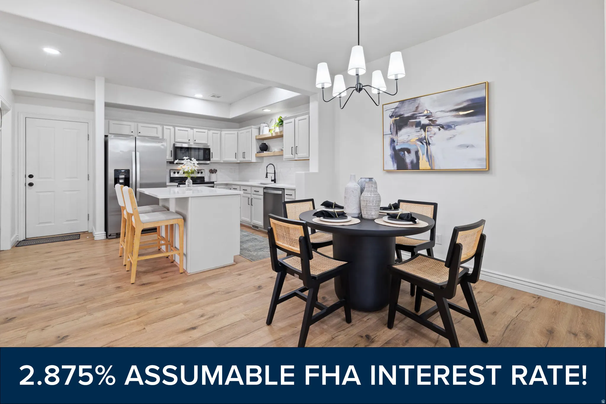 Open-concept living space with wood-finish flooring, a white kitchen featuring stainless steel appliances, and a dining area illuminated by a modern chandelier