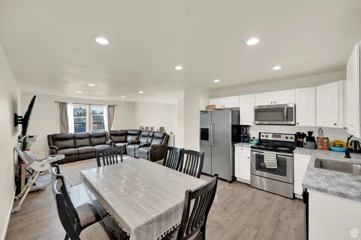 Kitchen with stainless steel appliances, white cabinets, open floor plan, decorative backsplash, and recessed lighting