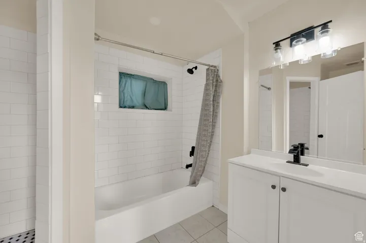 Full bathroom featuring vanity, shower / bath combination with curtain, and light tile patterned floors