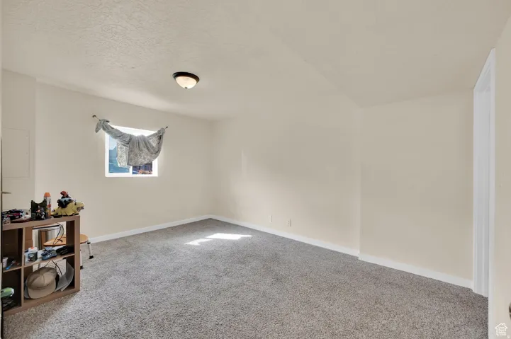 Empty room with carpet floors and a textured ceiling