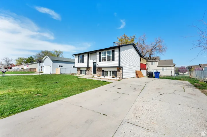 Raised ranch featuring stone siding and concrete driveway