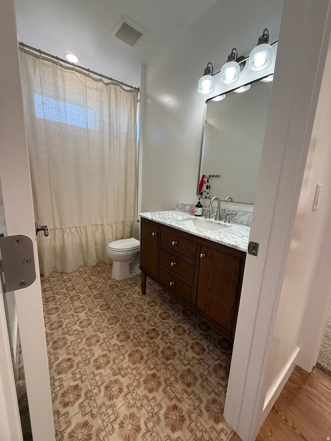 Bathroom featuring a single vanity with a dark wood-finish cabinet, a light-toned countertop, and a rectangular mirror