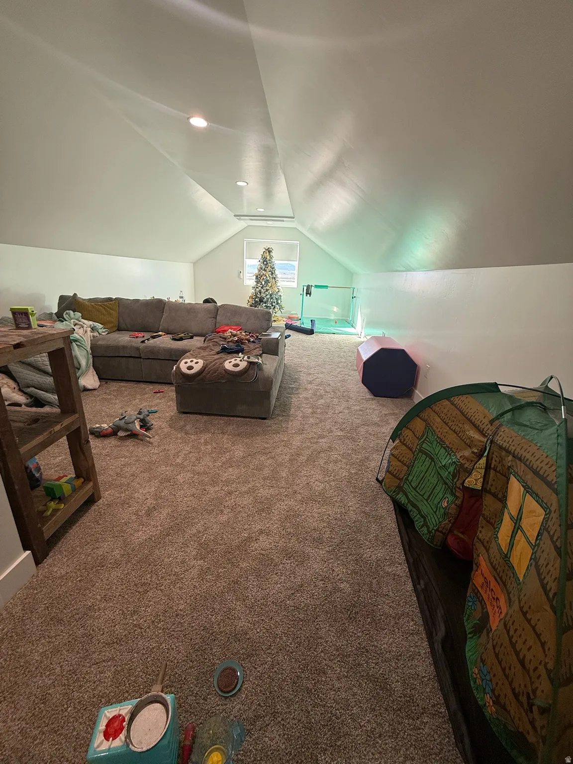 Spacious attic room featuring recessed lighting, a window providing natural light, sloped ceilings, and plush carpet flooring