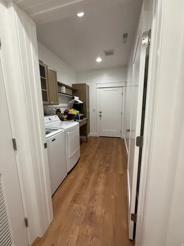 Laundry area featuring wood-finish flooring, recessed lighting, and white walls