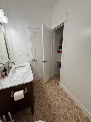 Bathroom featuring a patterned tile floor, a dark wood-finish vanity with a white marble countertop, an undermount sink, and a brushed nickel faucet