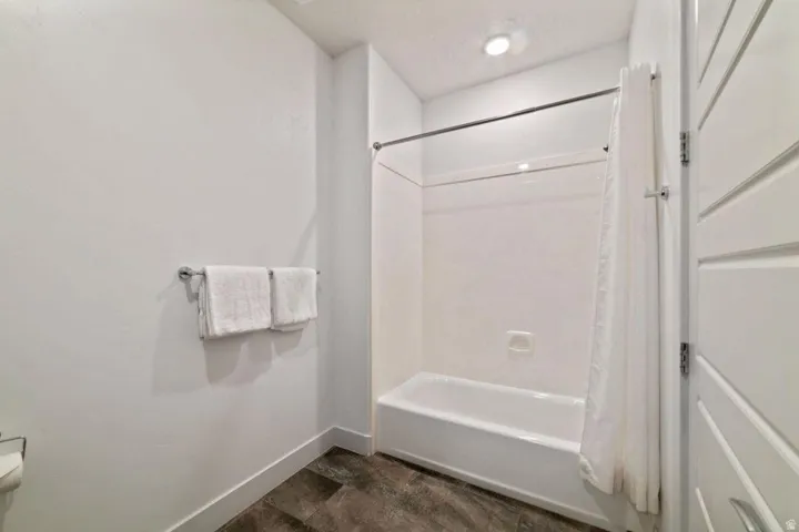 Full bathroom with shower / tub combo with curtain and baseboards