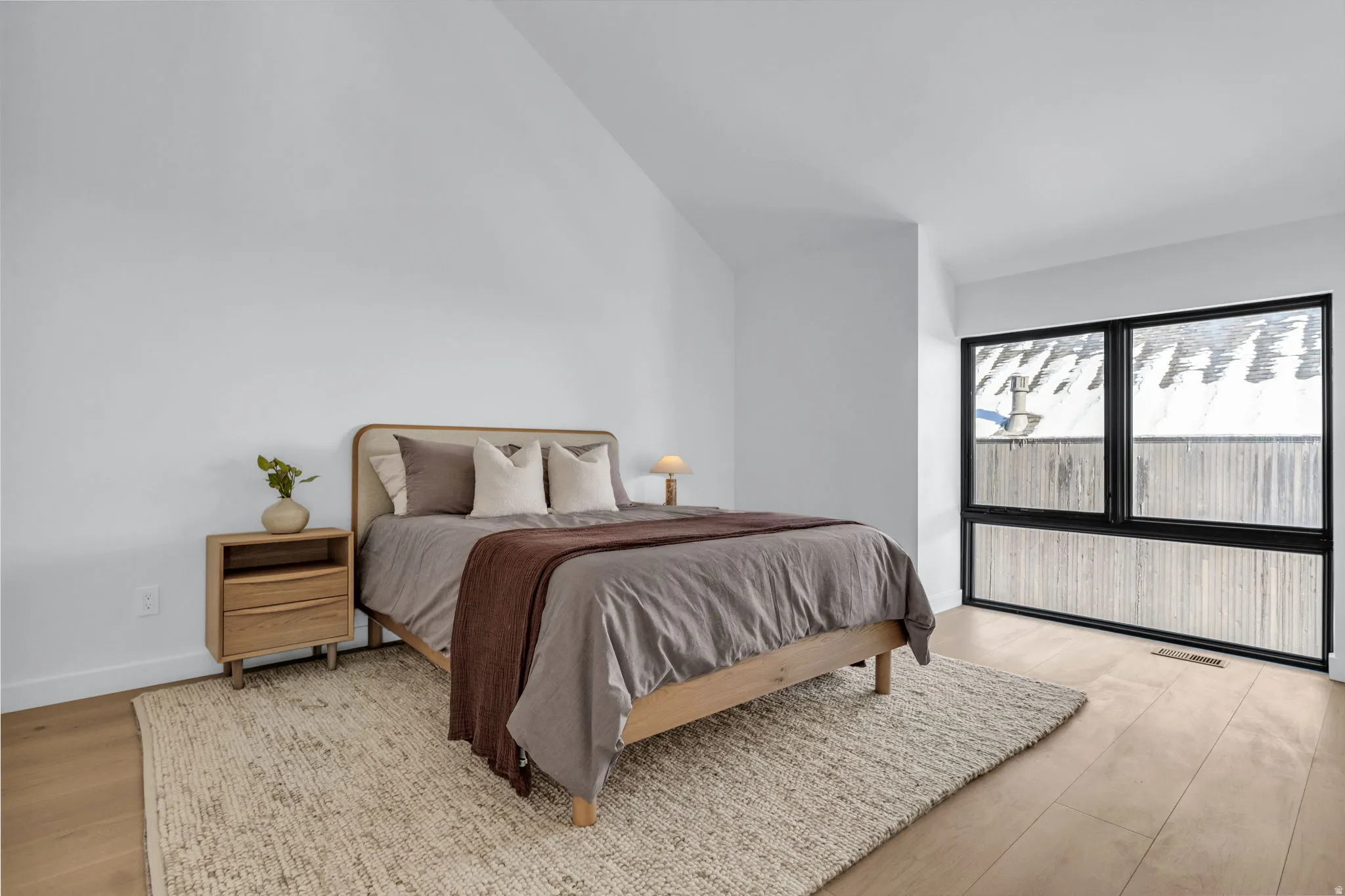 Bedroom with light wood-style flooring and lofted ceiling