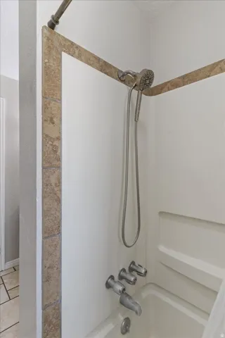 Bathroom with bathing tub / shower combination and light tile patterned floors