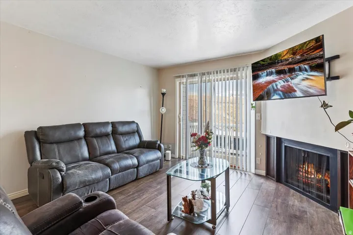 Living area with a lit fireplace, wood-style finished floors, and a textured ceiling