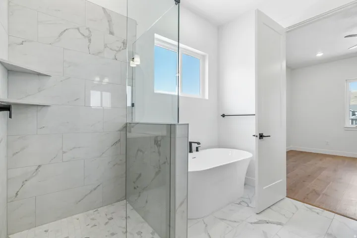 Bathroom with light marble finish flooring, a freestanding bath, and walk in shower