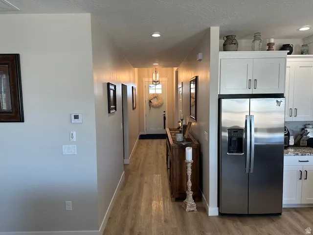 Hallway with a textured ceiling, light wood-style flooring, and recessed lighting