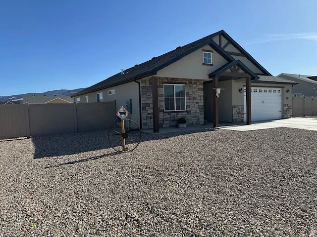 View of front of house with a garage, concrete driveway, stucco siding, and stone siding
