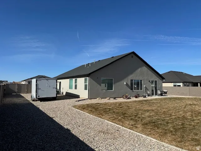 Back of house featuring a fenced backyard, a shed, a patio area, and stucco siding