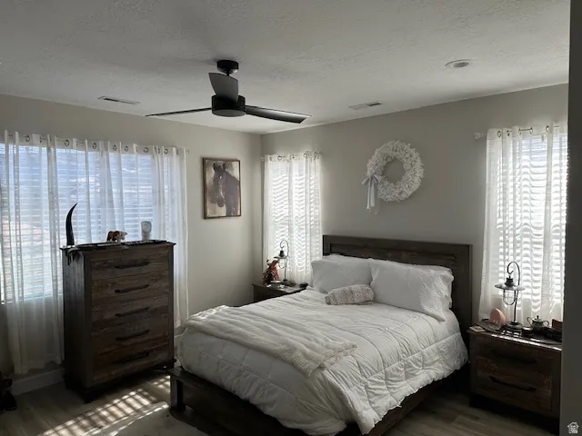Bedroom featuring wood finished floors, a textured ceiling, and a ceiling fan