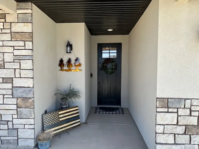 Entrance to property with stucco siding and stone siding