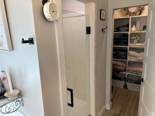 Bathroom featuring a stall shower, light wood-style floors, and a spacious closet