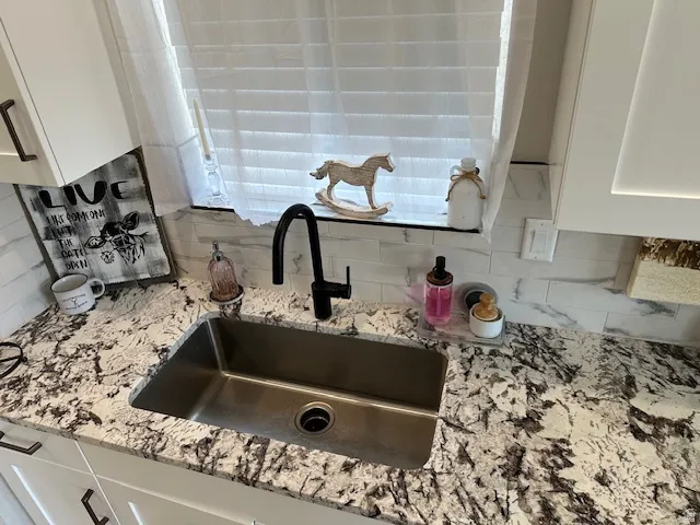 Kitchen view of light stone counters and white cabinetry