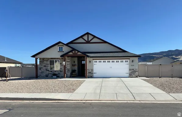 View of front of home featuring stone siding, concrete driveway, stucco siding, and an attached garage