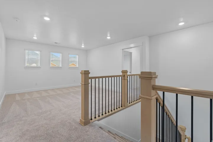 Corridor featuring an upstairs landing, light carpet, and recessed lighting
