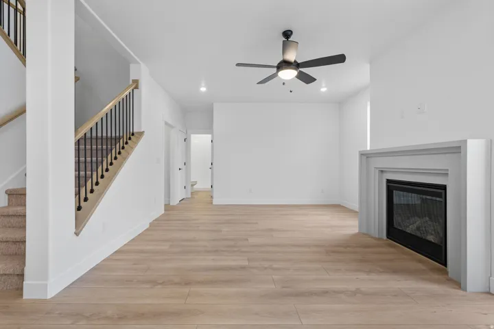 Unfurnished living room featuring light wood-type flooring, a glass covered fireplace, ceiling fan, and recessed lighting