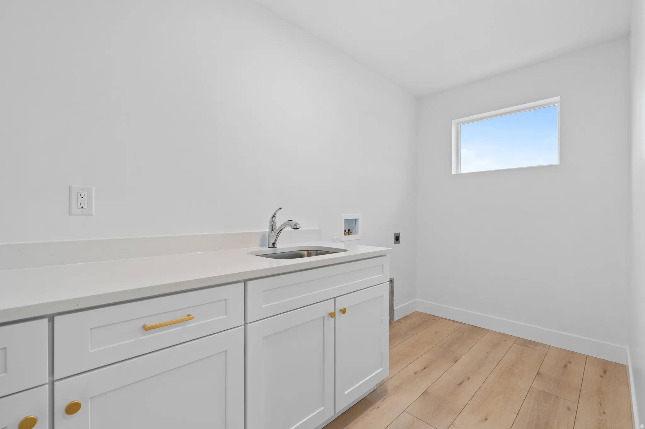 Laundry area with light wood finished floors, cabinet space, hookup for a washing machine, and electric dryer hookup