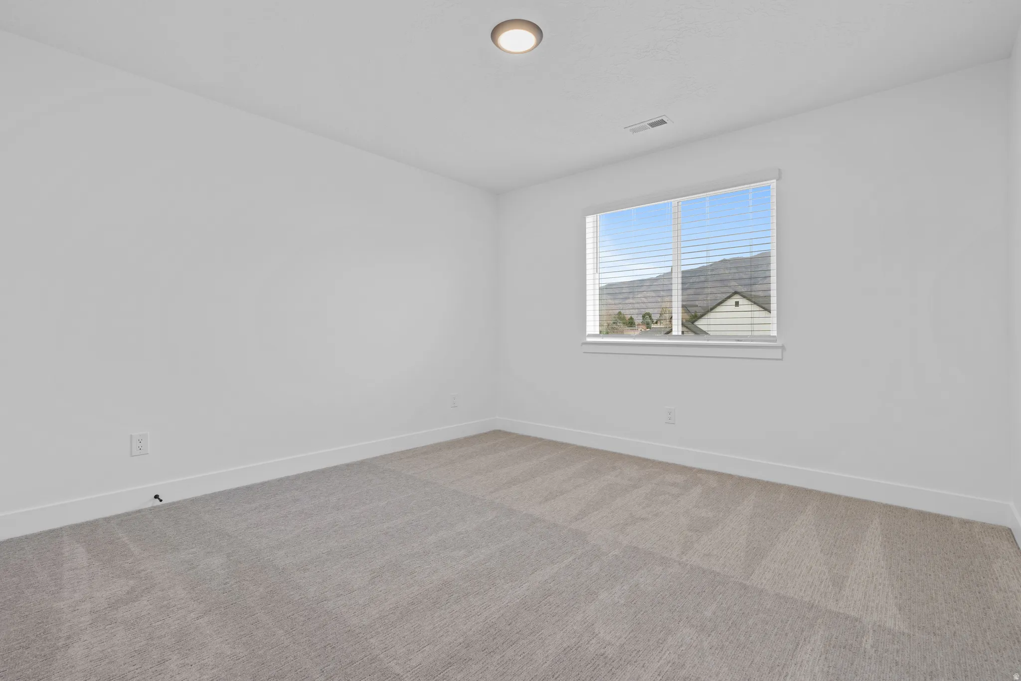 Spare room featuring baseboards and light colored carpet