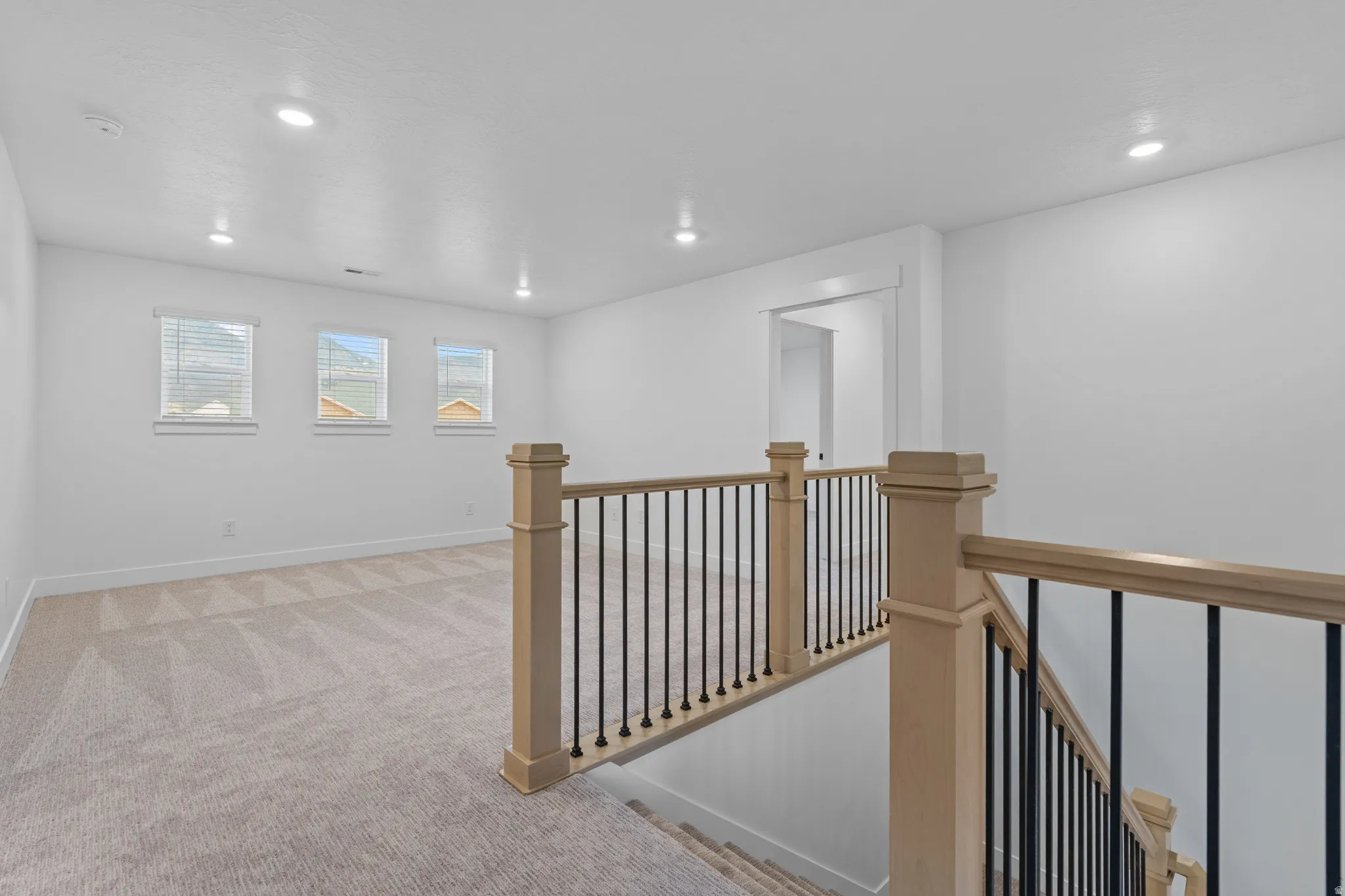 Corridor featuring an upstairs landing, light carpet, and recessed lighting