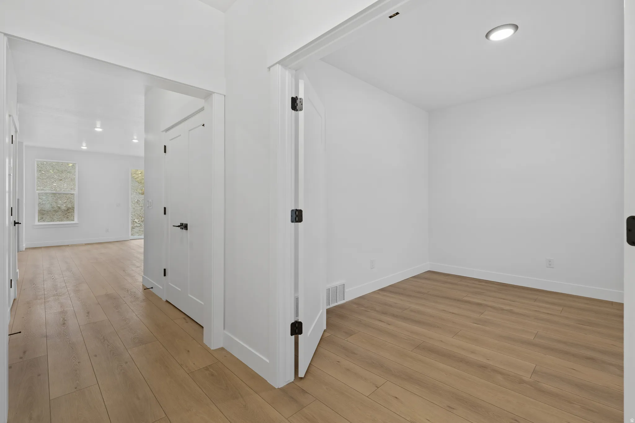 Hallway with light wood finished floors and recessed lighting