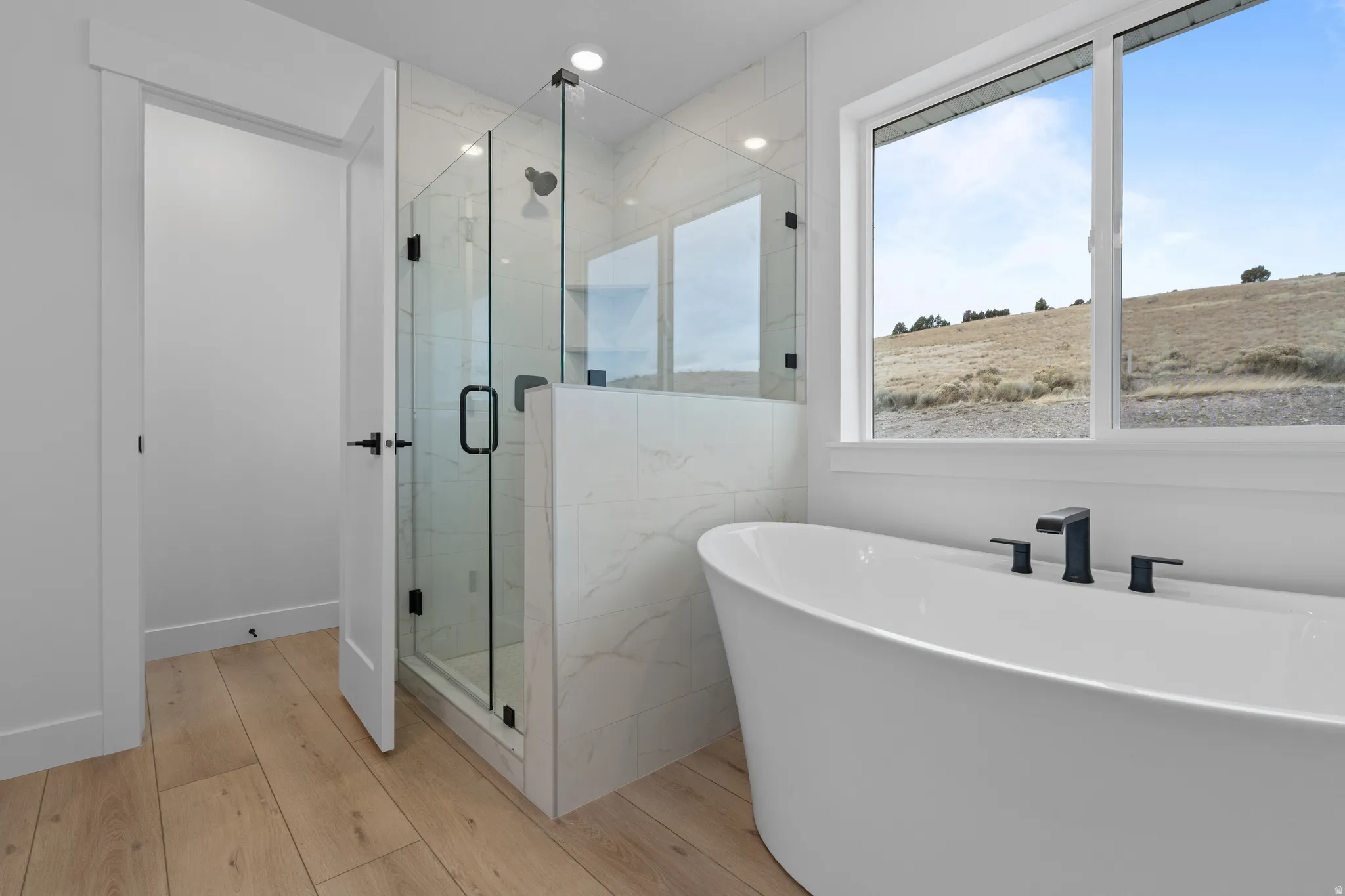 Full bath with a marble finish shower, light wood-style flooring, a soaking tub, and recessed lighting